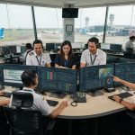 Petugas operasional bandara sedang memantau manajemen sistem menggunakan modul utama AVAGOS di ruang kontrol modern