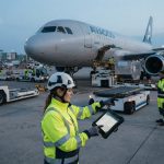 Petugas bandara menggunakan tablet untuk transformasi digital ground handling AVAGOS di apron bandara