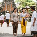 Orang-orang mengenakan busana adat lengkap sesuai aturan berpakaian ke pura di Bali