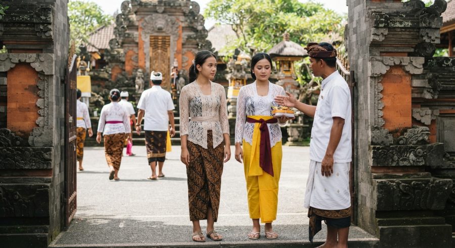 Orang-orang mengenakan busana adat lengkap sesuai aturan berpakaian ke pura di Bali